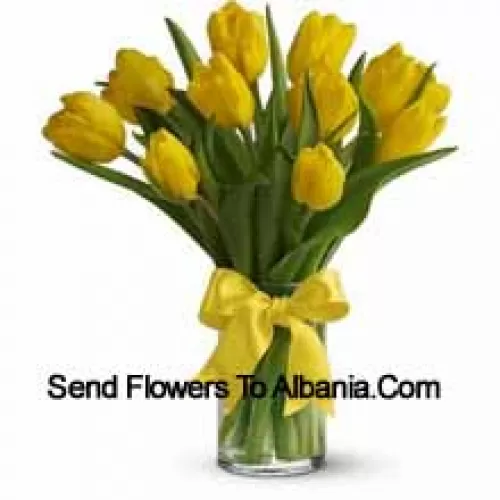 Желтые тюльпаны с сезонными наполнителями и листьями в стеклянной вазе - Обратите внимание, что в случае отсутствия определенных сезонных цветов их будут заменены другими цветами того же значения